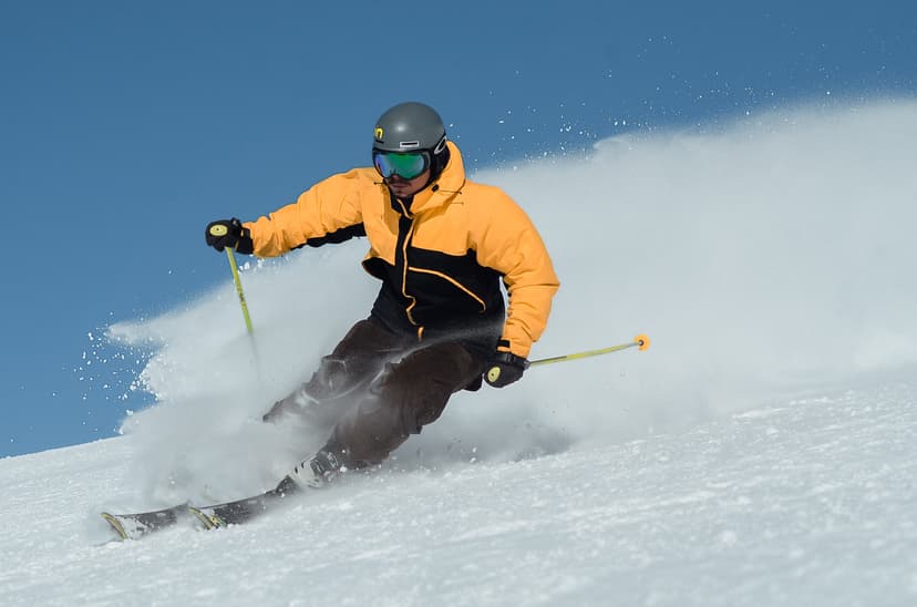 Skier speeding down piste in yellow jacket