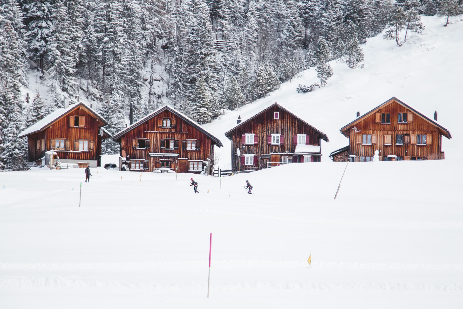 row-of-wooden-chalets-skiers