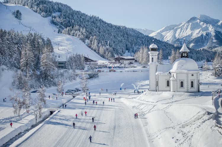 Skiiers skiing past traditional church in Seefeld ski resort