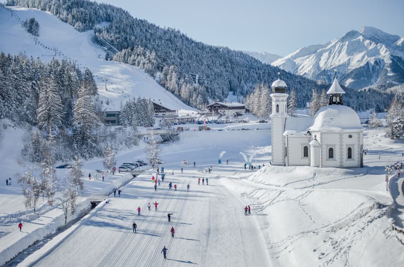 Skiiers skiing past traditional church in Seefeld ski resort