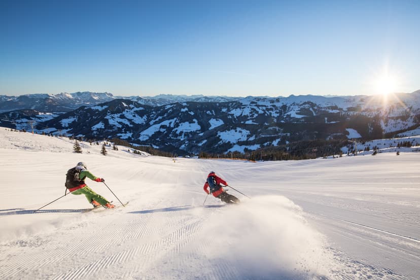 Skiiers enjoying ski slope in Austria at sunset