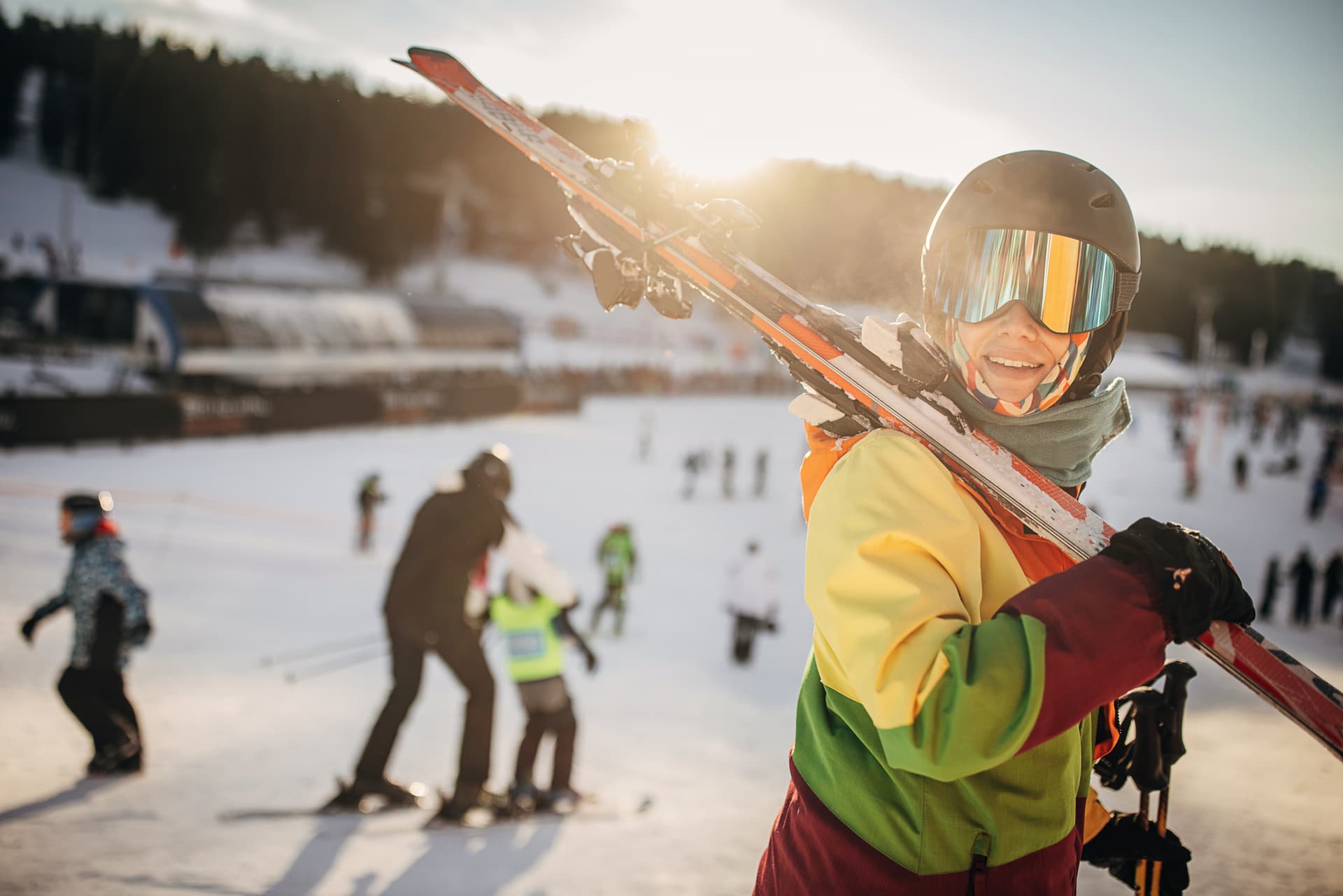 Female skier carrying skis after day of skiing at sunset