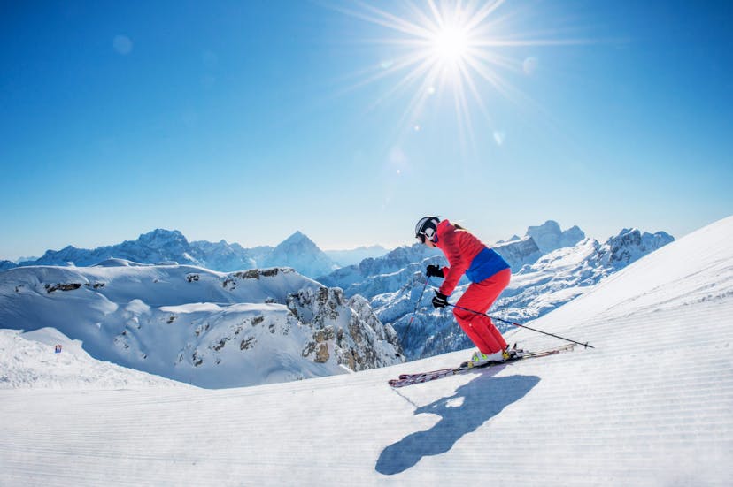 Skier carving down frehsly groomed ski piste in Italian Dolomites