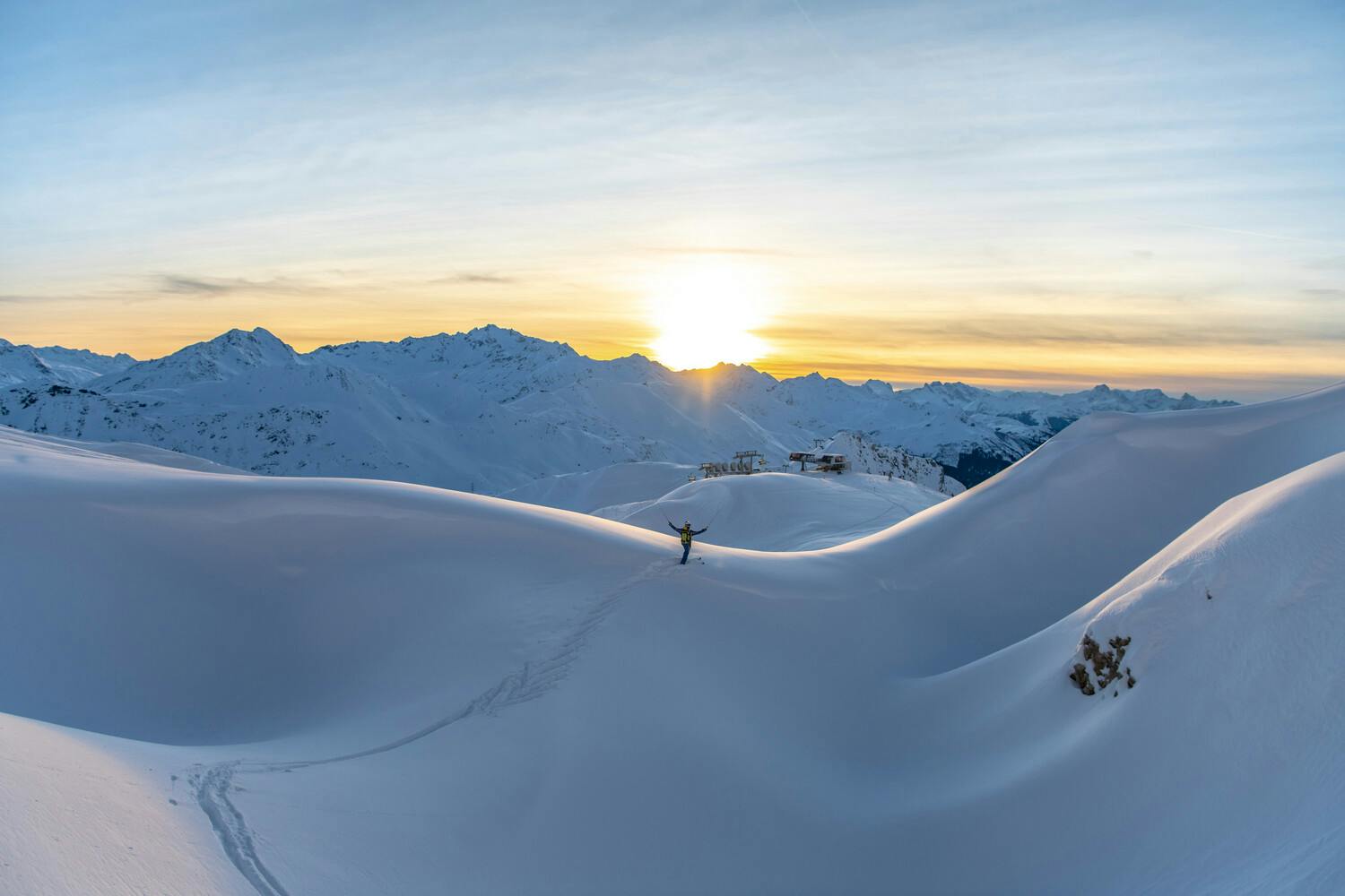 Isolated skiier raising arms at stunning sunset scenery in St Anton