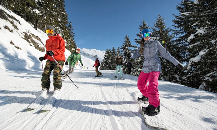 Group of friends skiing down tree lined slope in La Clusaz