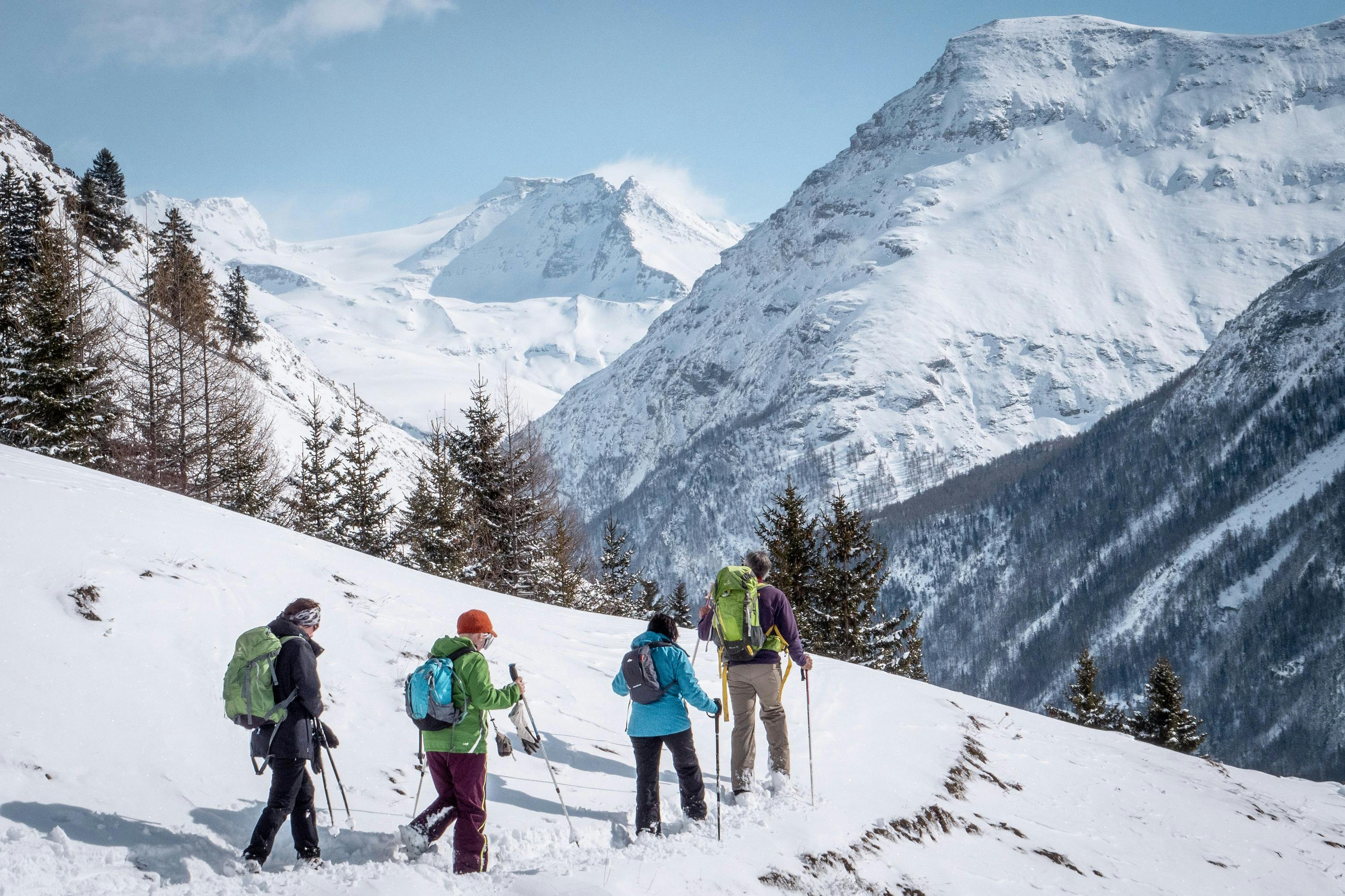 Group of friends snow shoe hiking across snowy mountain in Val Cenis ski resort