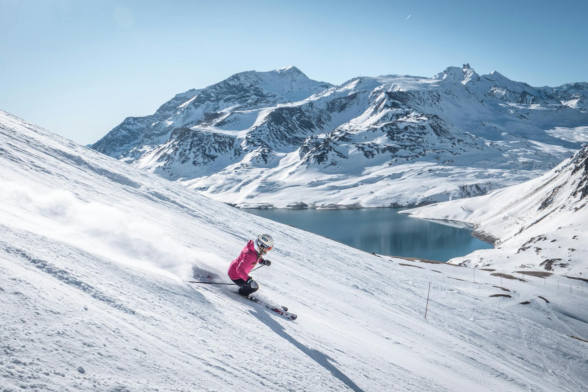 Woman skiing down slope next to lake in French Alps