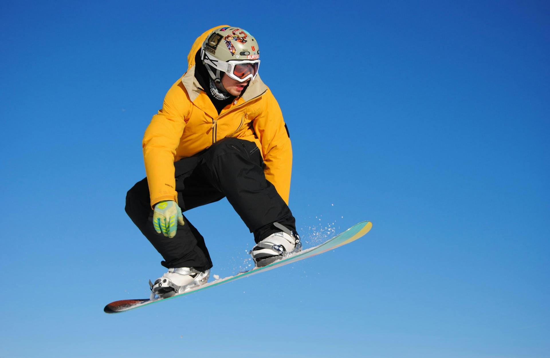 Snowboarder in orange jacket jumping through air at ski resort