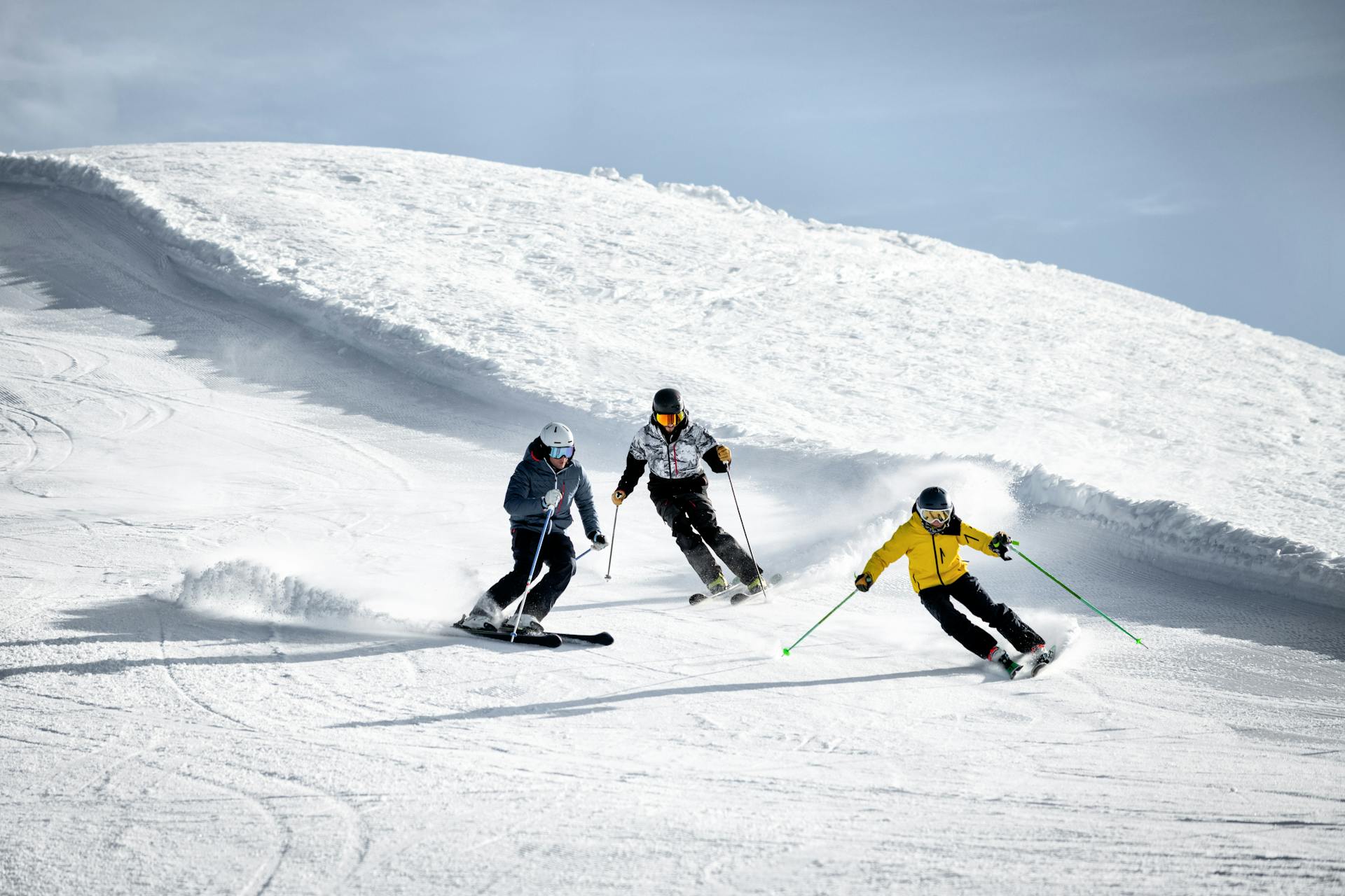 Three skiers racing down mountain together on intermediate slope
