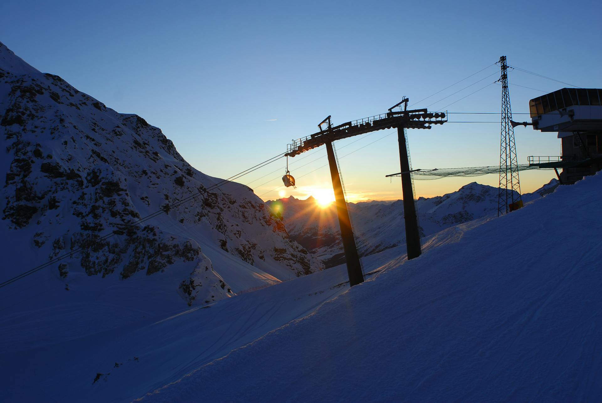 Chairlift transporting skiers to top of Italian mountain ski slope at sunset
