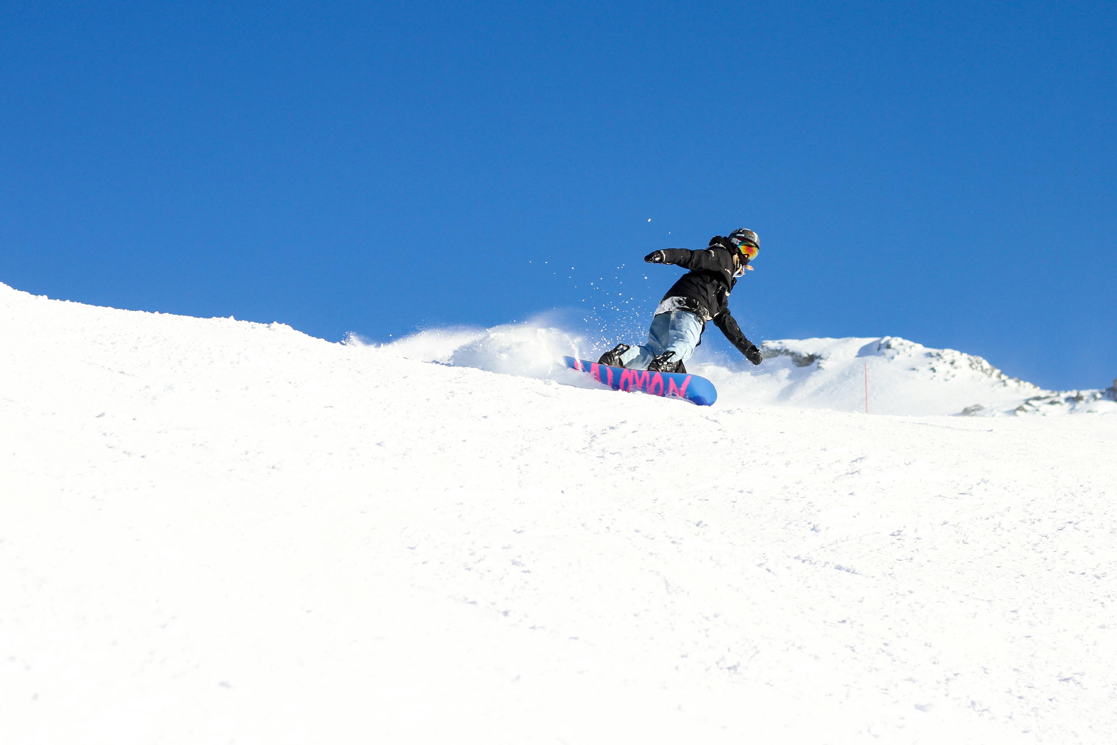 snowboarder carving down ski slope