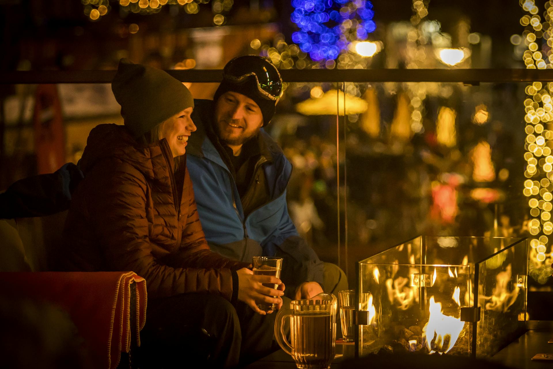 Couple having drink at apres bar by fire after skiing