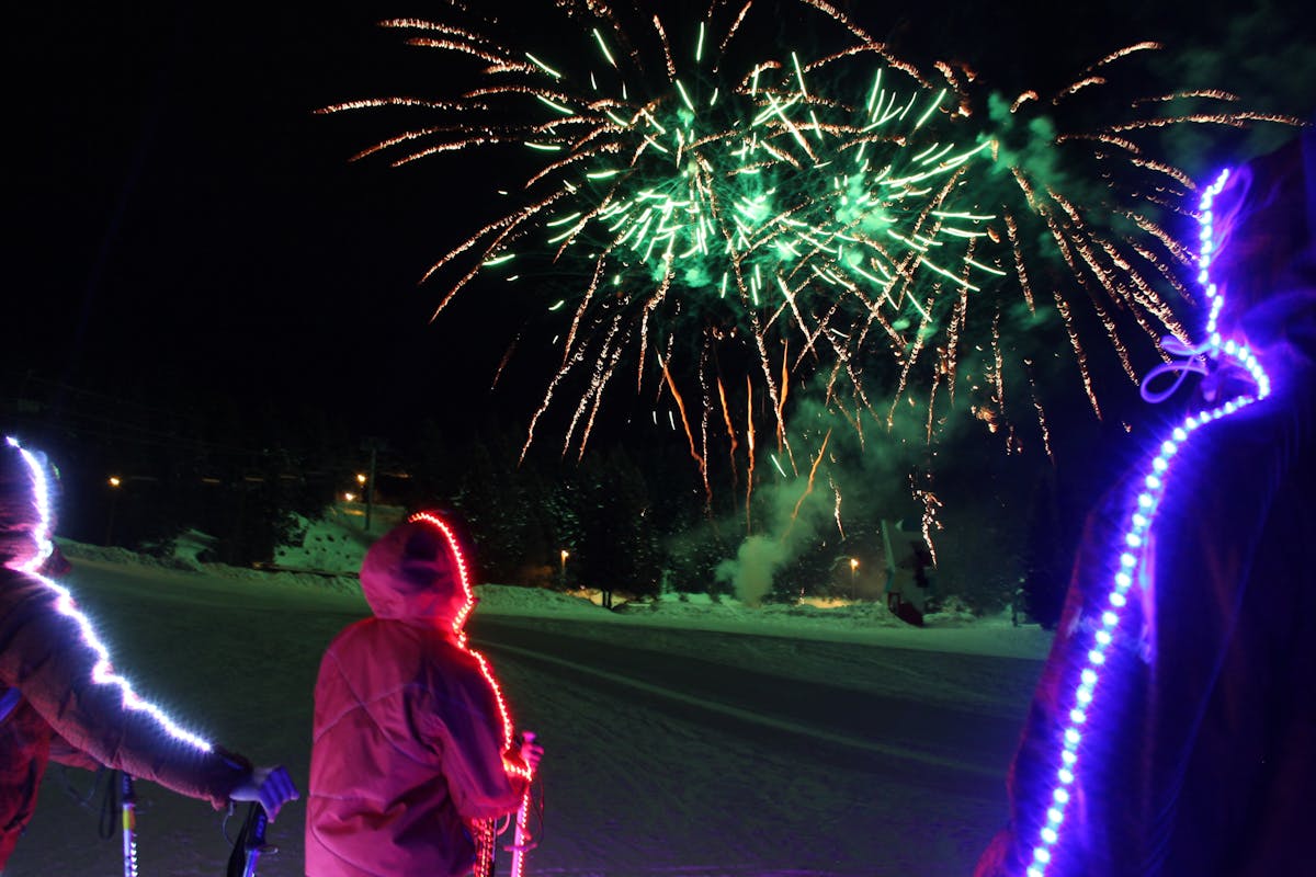 Family watching fireworks in Chamrousse ski resort at night