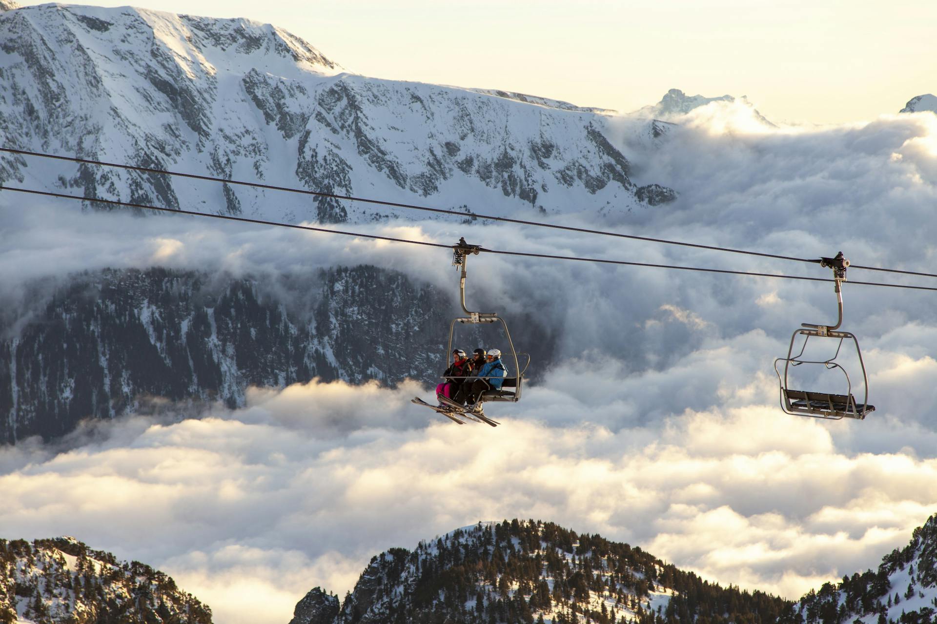 Chairlift transporting skiiers up mountain above clouds