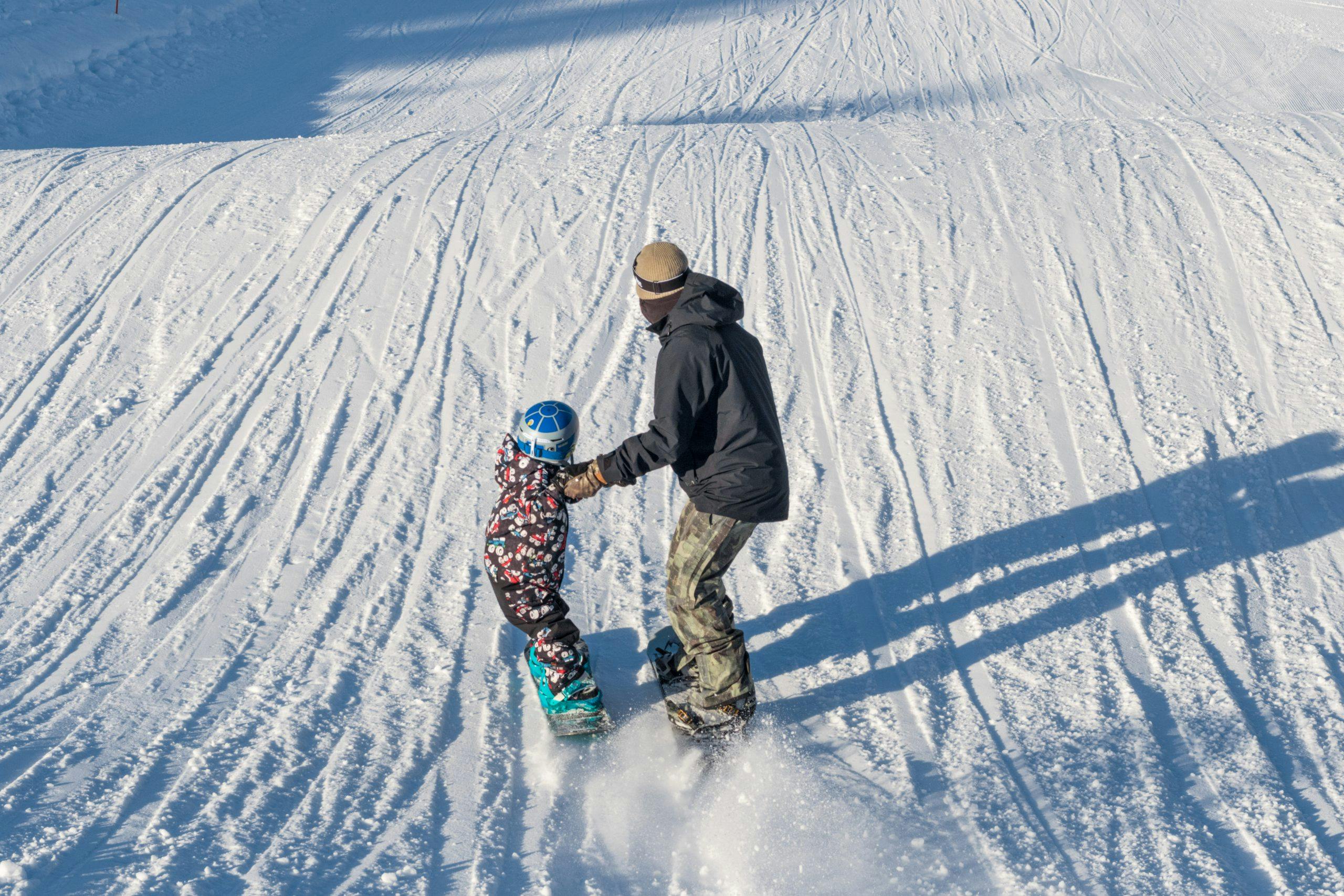 Father teaching child how to snowboard
