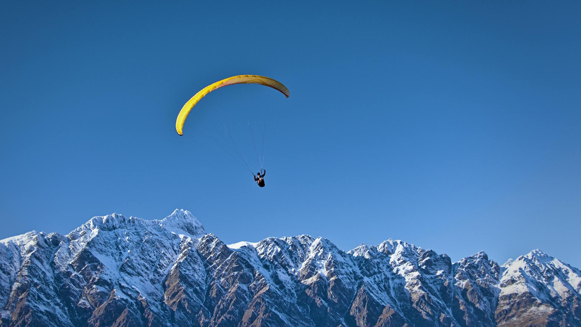 Man soaring above mountains while paragliding 