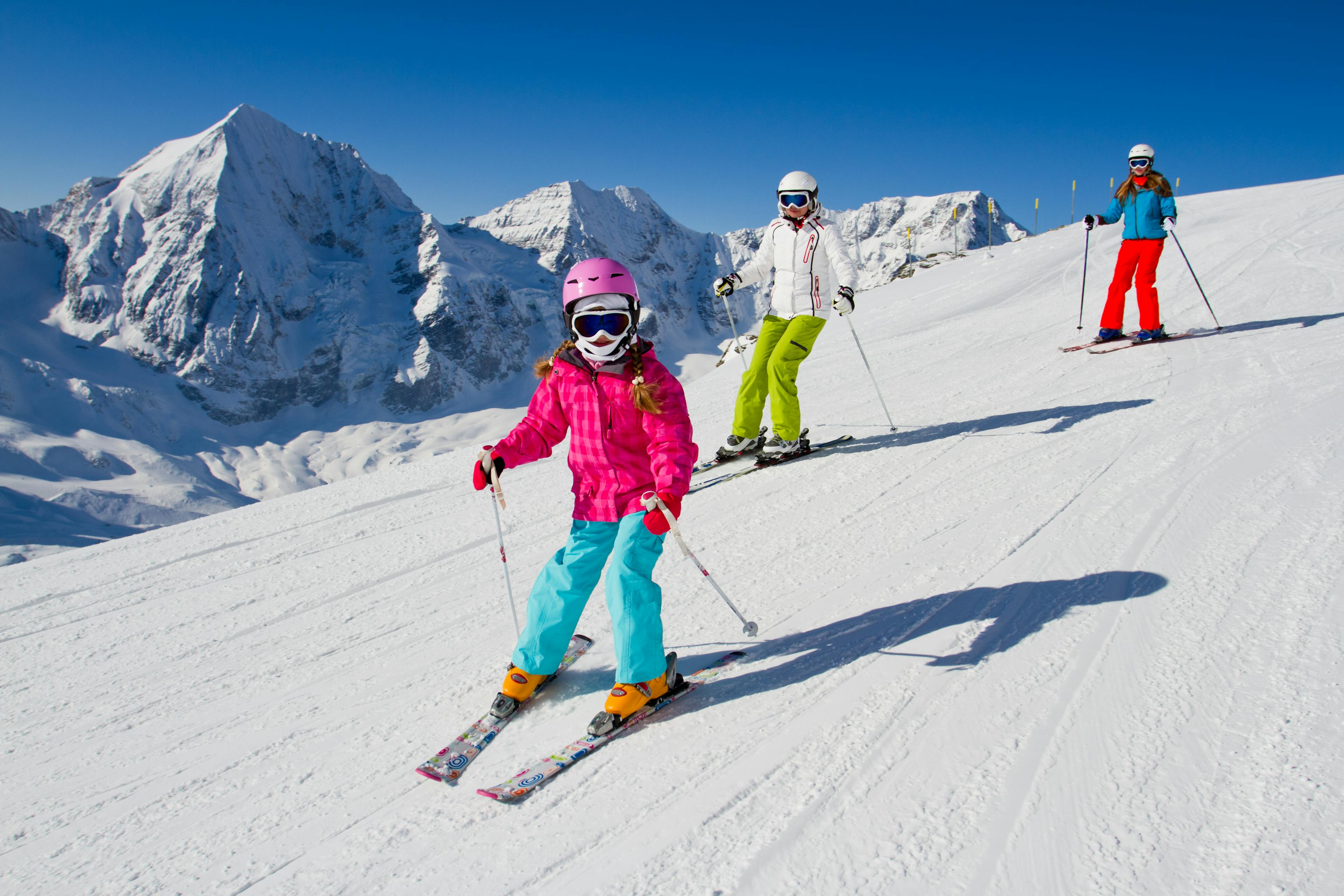 Family skiing down cat track ski slope