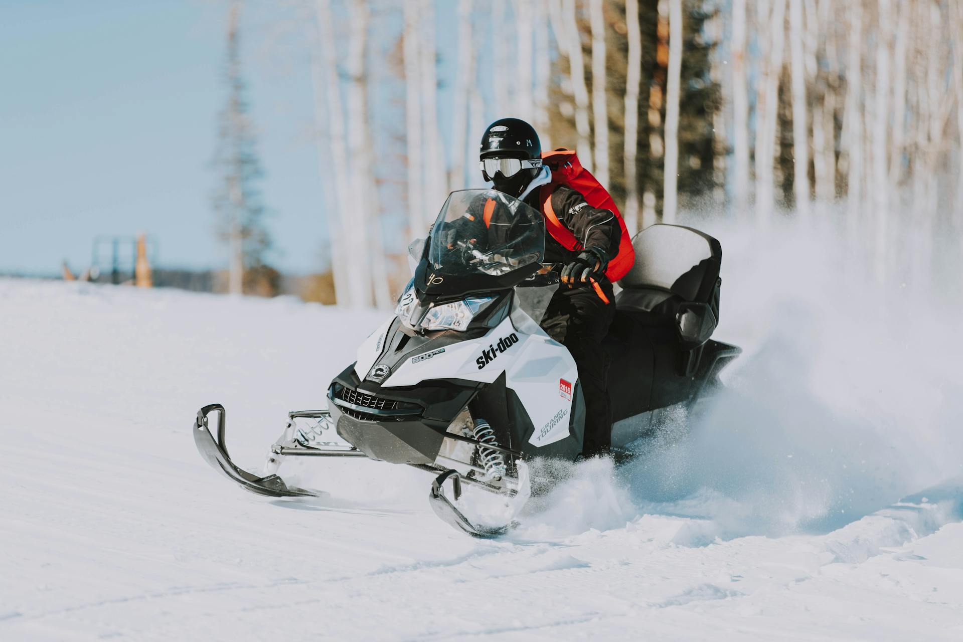 Man driving a snowmobile across snowy path