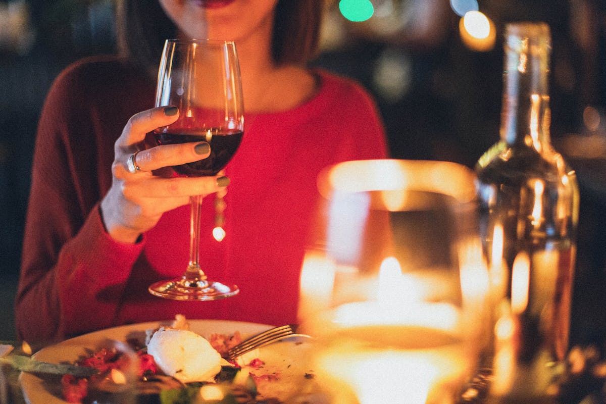 Woman drinking a glass of red wine with her evening meal