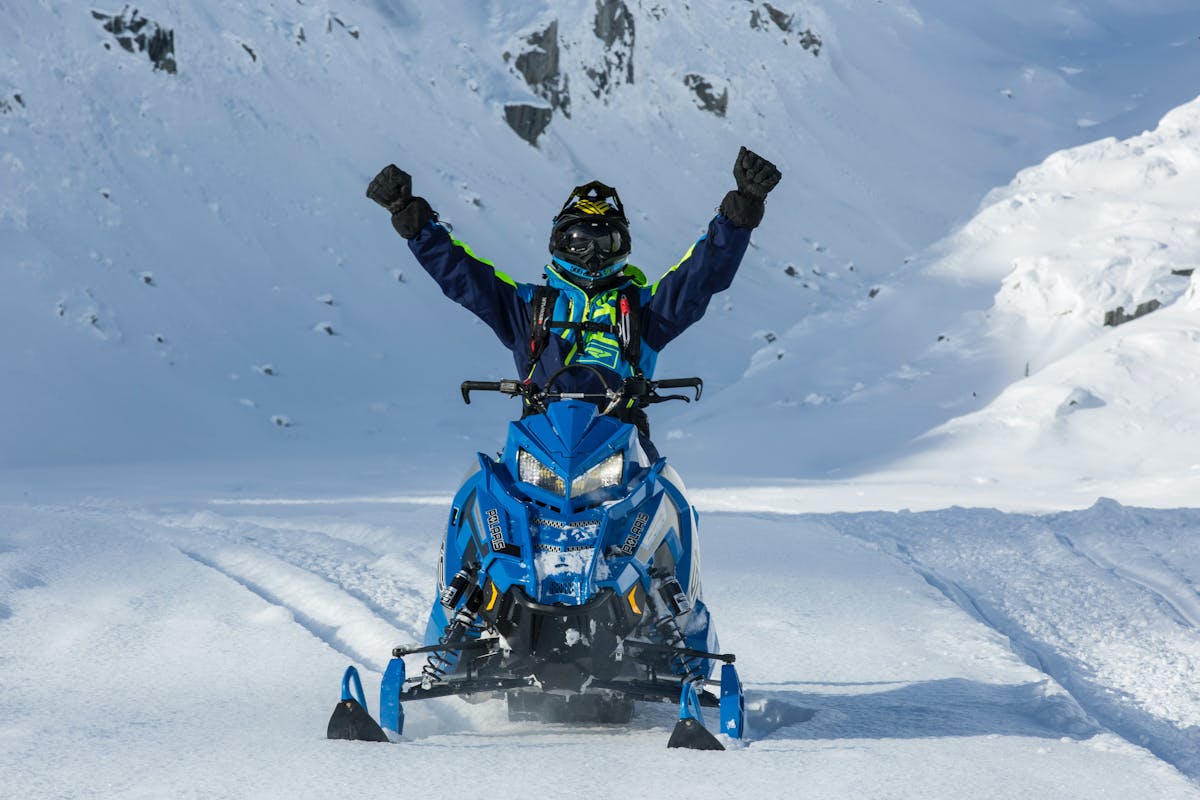 Man raising arms in joy after snow mobile riding at ski resort on holiday