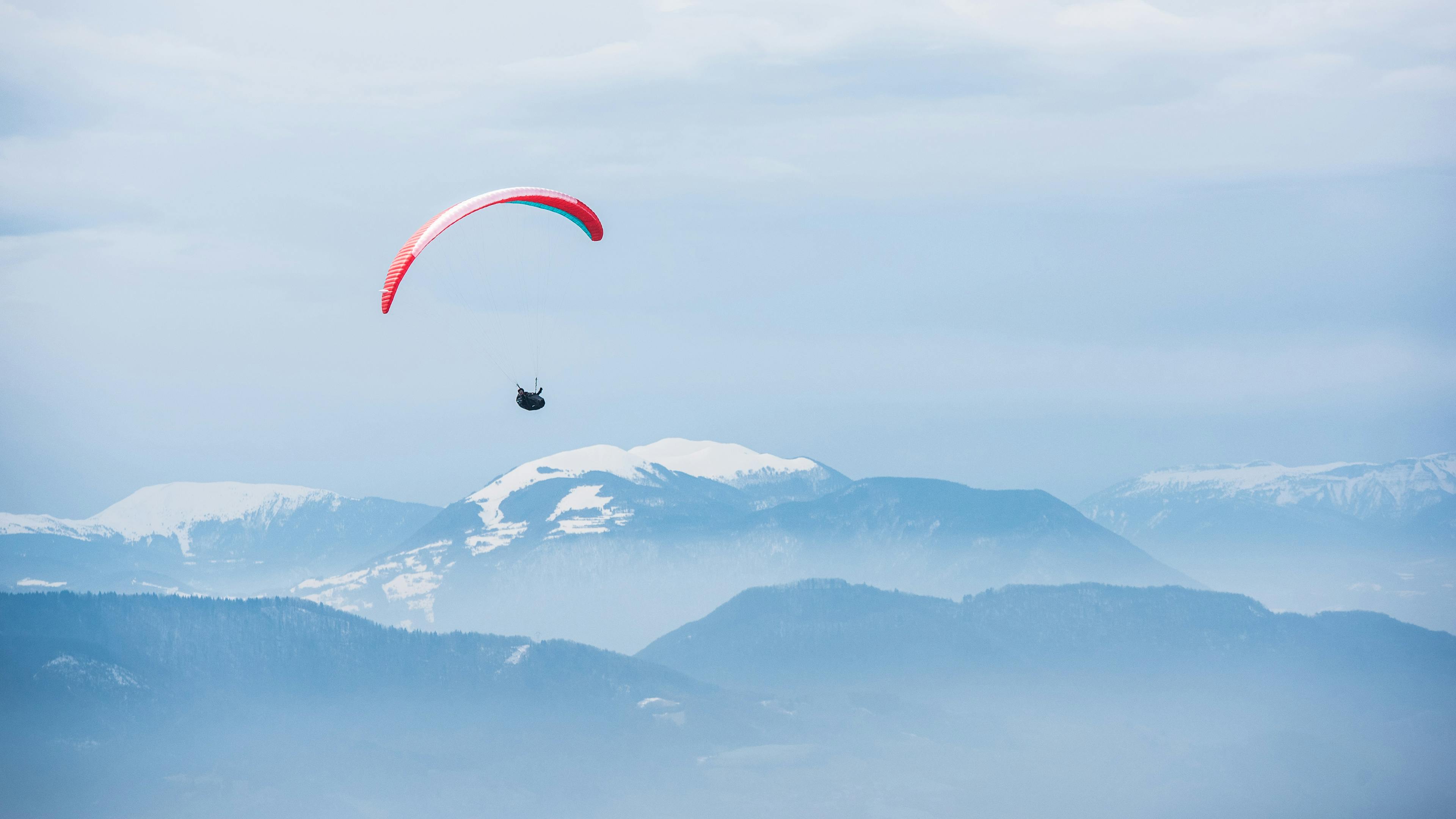 Paraglider enjoying scenic views over snowy mountains