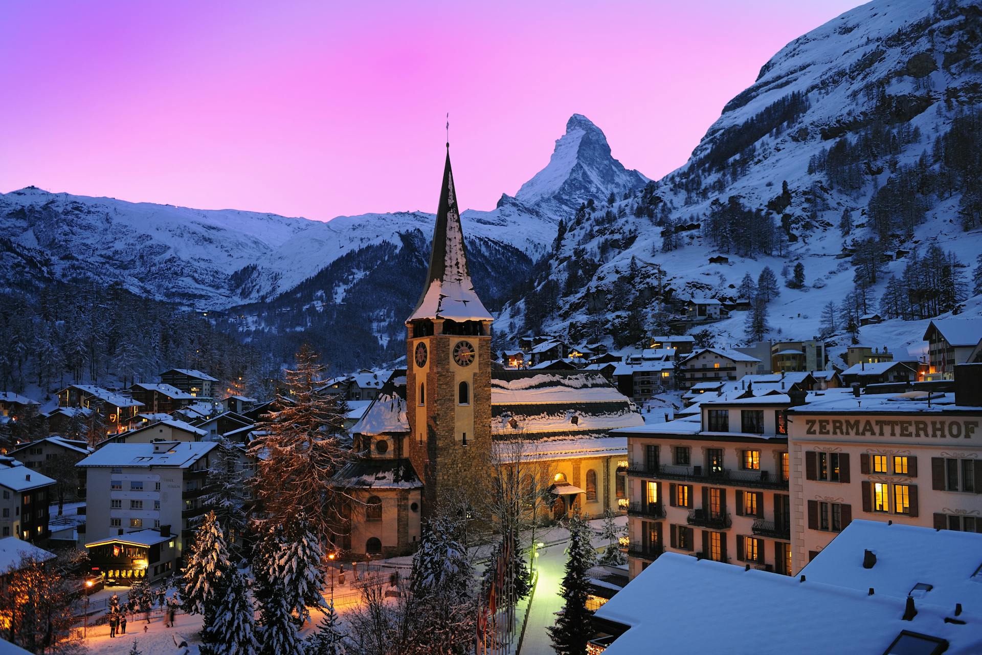 Traditional church and town of Zermatt ski resort in winter at sunset