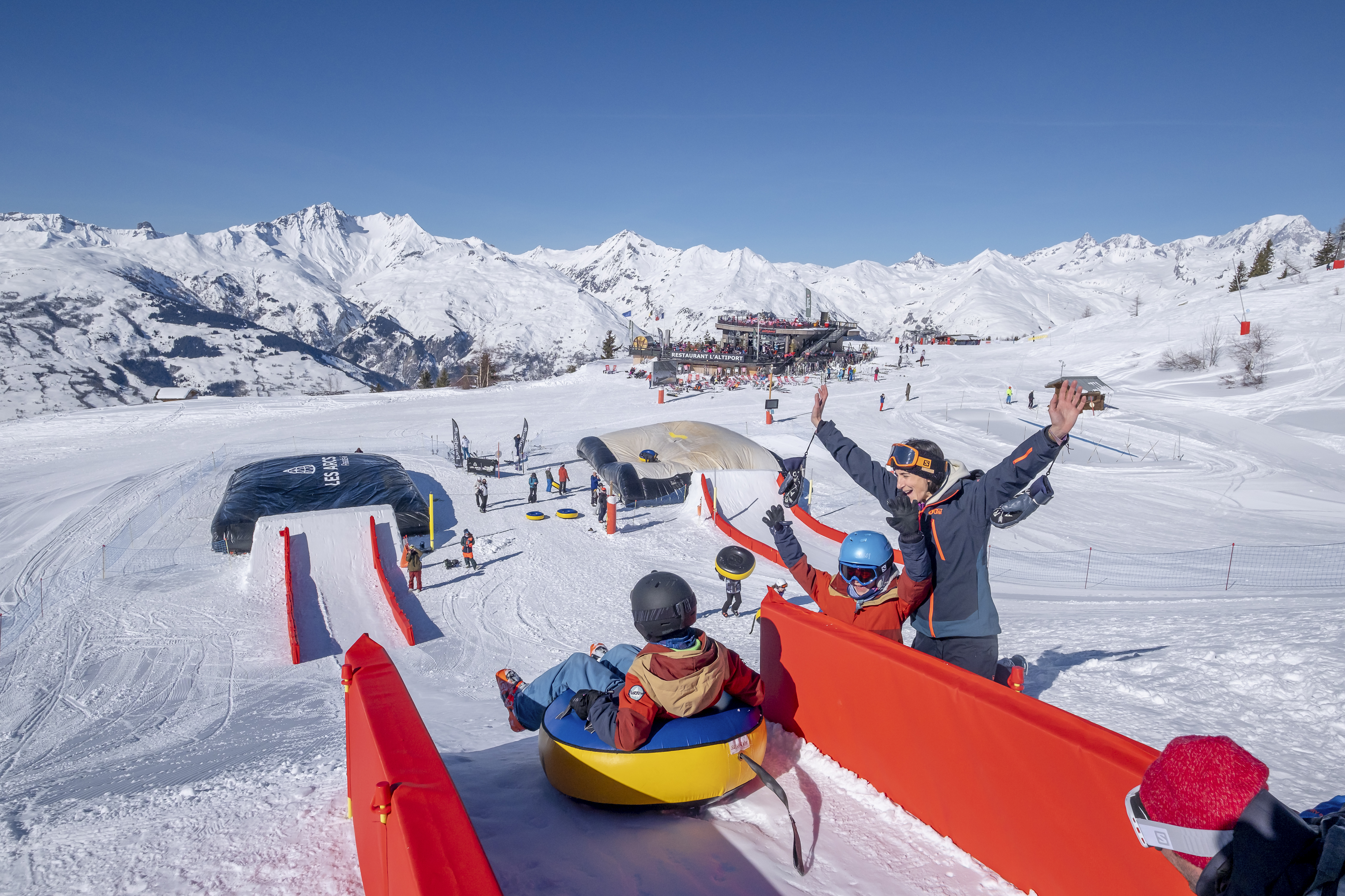 Children having great fun snow tubing down slide in Les Arcs