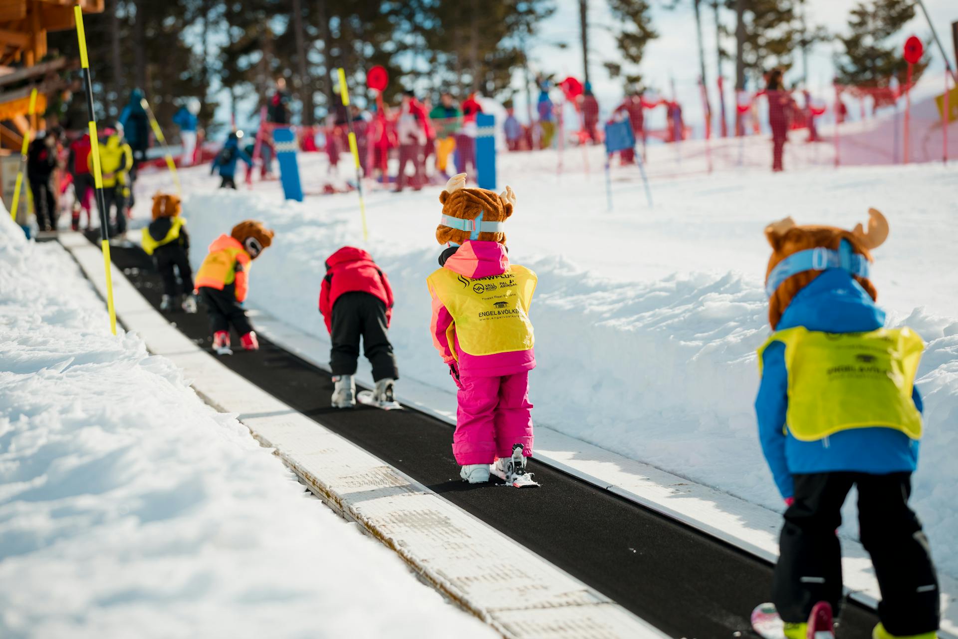 Young children travelling in magic carpet while learning how to ski