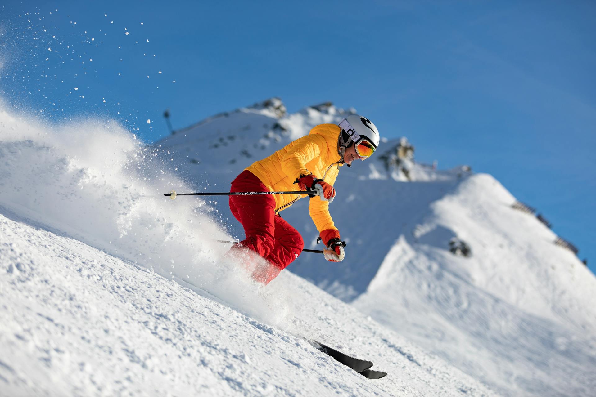 Woman in orange jacket skiing down ski slope