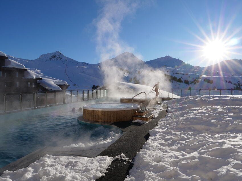 Woman leaving thermal pool surrounded by snow in La Plagne Ski Resort