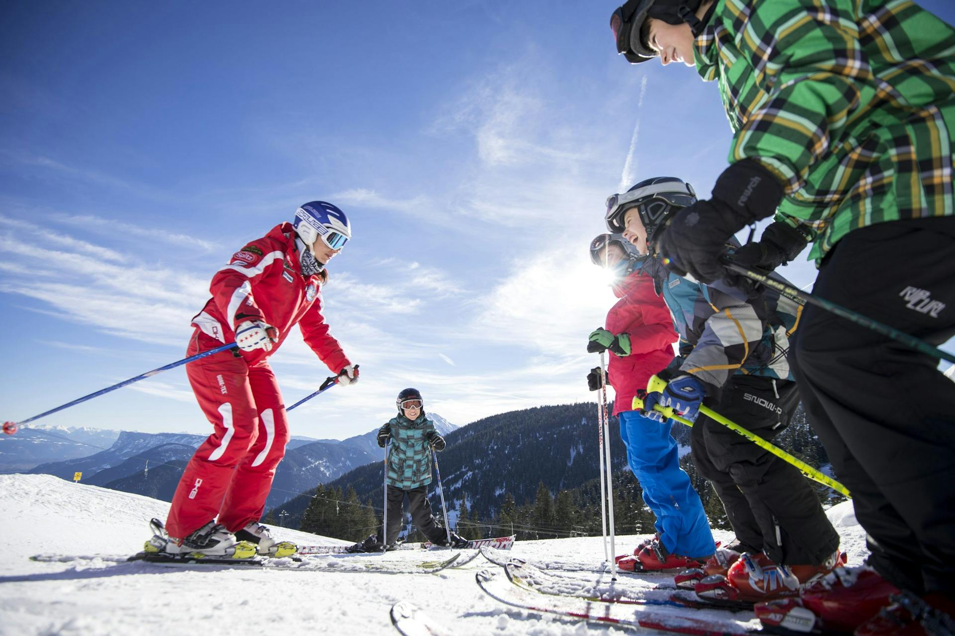 Ski instructor teaching laughing children to ski